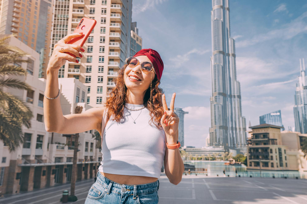 Happy tourist taking a selfie in front of the Burj Khalifa in Dubai